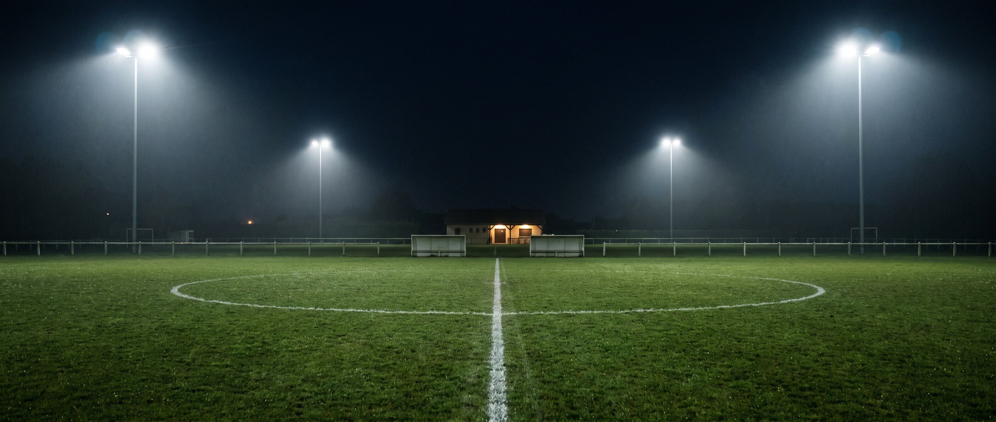 Un terrain de foot amateur désert, la nuit, sous les projecteurs